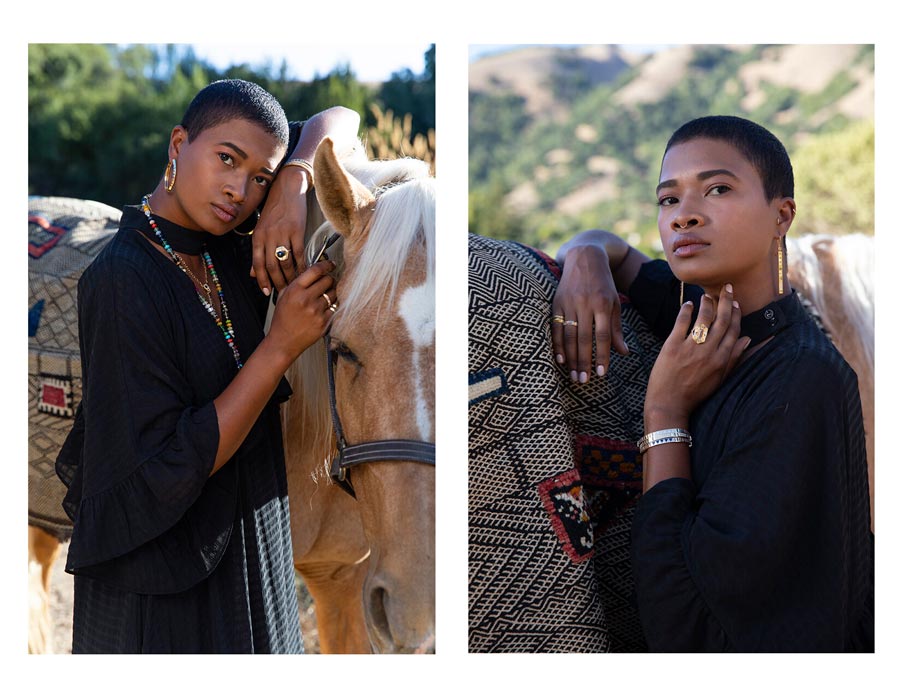 Woman leaning on horse outdoors looking at camera wearing rings, earrings, bracelets, stone beaded necklace for Good Juju Collection